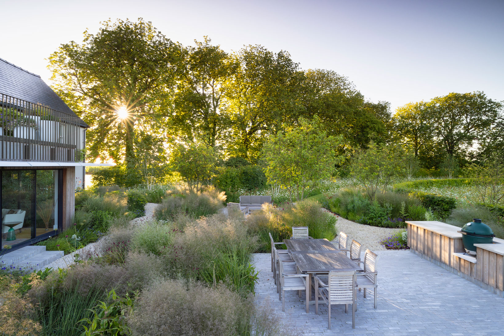 Colm Joseph Cambridgeshire country garden house modern extension dining seating limestone pavers outdoor kitchen timber perennial planting design deschampsia morning light