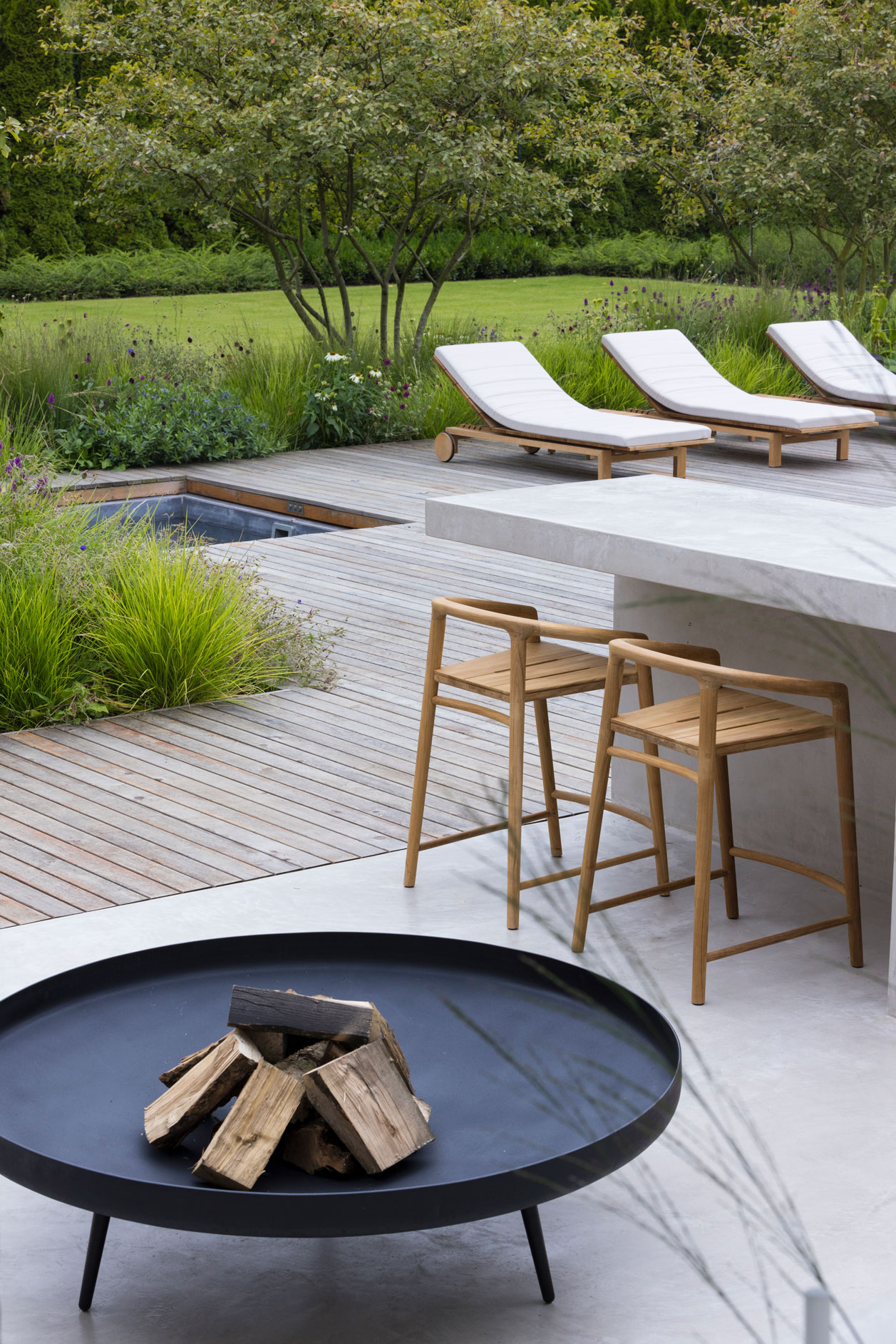 Colm Joseph modern country garden home cambridgeshire concrete outdoor kitchen cantilevered kitchen counter firebowl sun loungers in-ground hot tub naturalistic planting design amelanchier trees